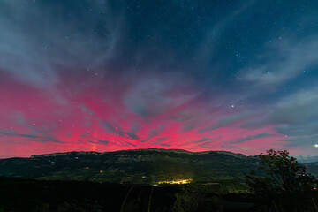 Vibrant red aurora borealis painting the night sky above Serra Del Montsec, Lleida, Spain. October...