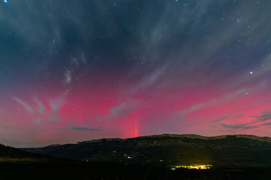 Vibrant red aurora borealis painting the night sky above Serra Del Montsec, Lleida, Spain. October 2024