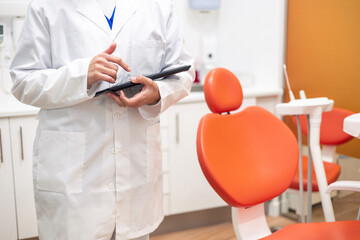 unrecognized Dentist using digital tablet in dental clinic with modern equipment © EDER