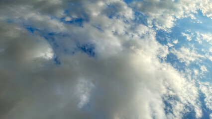 Soft, billowing clouds scattered across a bright blue sky, showcasing a serene and dreamy natural atmosphere with subtle light and texture.