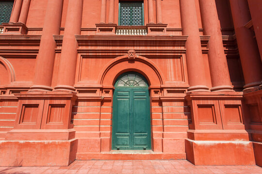 Big red house with columns and old wooden door in front.