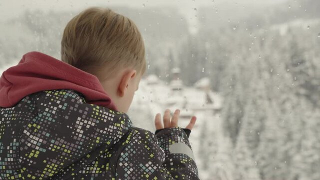 Refocus. A little boy looks at the mountain landscape from the cab of a Ferris wheel