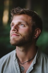 Obraz premium Young man with beard, gazing upward, outdoors.