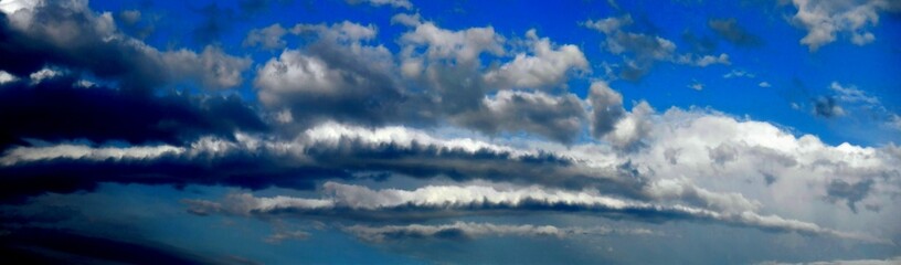 Blue sky and white and grey clouds Stratocumulus Volutus - panorama view, abstract sky background with natural pattern of clouds. Topics: weather, meteorology, abstraction, nature, wallpaper, climate