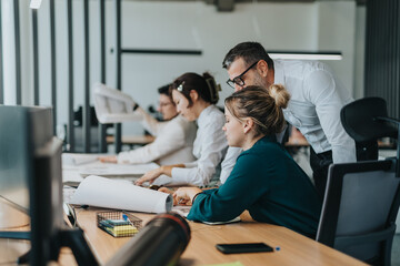 A diverse group of people working together in an open office setting. They appear focused and...