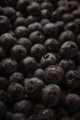 a close-up photograph of a large group of fresh blueberries. The berries are tightly packed together, filling the entire frame. Many of the blueberries have tiny droplets of water 
