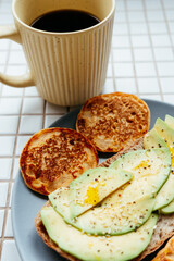 coffee, pancakes, avocado toast on plate on the kitchen table, breakfast on a sunny morning. healthy eating, vegetarian. top view of the food. nutritious lunch, delicious and balanced.