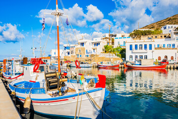 Colorful fishing boats anchoring in Katapola port with white Greek houses in background, Amorgos...