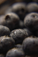 a close-up photograph of a cluster of blueberries. The berries are tightly packed together, filling the frame almost entirely. The dominant color is a deep, dusty blue