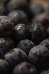 a close-up photograph of a cluster of blueberries. The berries are tightly packed together, filling the frame almost entirely. The dominant color is a deep, dusty blue