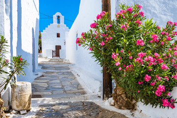 Naklejka premium Narrow alley with flowers leading to white church in Chora village, Amorgos island, Cyclades, Greece