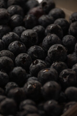 a plastic container filled with fresh blueberries. The container is likely sitting on a wooden surface, given the visible wood grain in the background