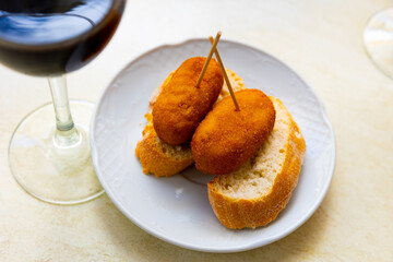 Simple and hearty snack is served on plate - two thick slices of bread and cutlets. Bamboo toothpicks are inserted into cutlets for convenience. Dish is complemented by glass of cold beer.