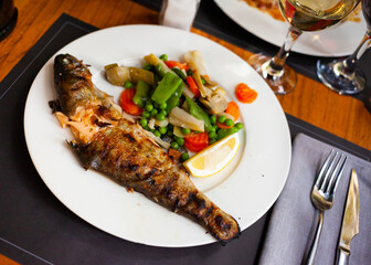 Delicious grilled trout with a slice of lemon and stewed vegetables