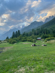 Hiking trail at dusk in Auronzo di Cadore near Cortina d&rsquo;Ampezzo, featuring rolling green meadows, a wooden chalet, and the iconic Tre Cime peaks in the Dolomites