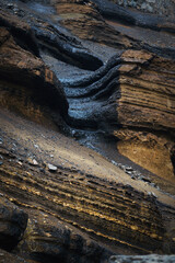 Close-up of layered basalt lava and red clay strata near Hengifoss waterfall, showcasing Iceland's...