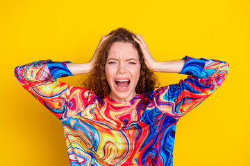 Young woman in vibrant print sweatshirt expressing frustration against yellow background