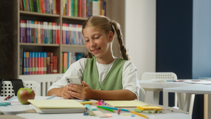 Student girl kid child pupil at classroom studying school education smiling teen Caucasian schoolgirl daughter blogger scrolling social media mobile phone internet smartphone addict online chat gpt