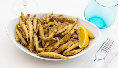 Fried anchovies with lemon on plate. Traditional spanish dish