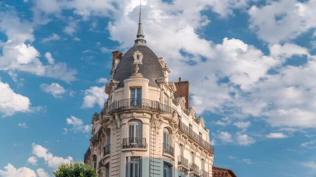 Historic facades at Rue du Languedoc and Theodore Ozenne intersection timelapse in Toulouse, France. Shops, cafes near Carmes metro station in vibrant city center under clouds on a blue sky