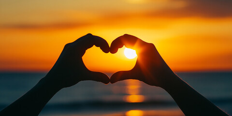 Creating a heart shape with hands against a stunning sunset over the ocean water. Valentines Day