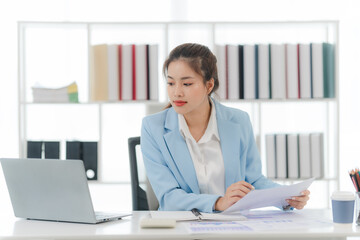 Focused on the Task: A professional woman in a light blue suit, engrossed in her work, analyzing...