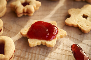 Filling traditonal Linzer Christmas cookies with red strawberry jam