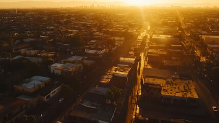 A wide drone shot of an LA ghetto at sunset with golden light reflecting off weathered buildings and winding streets.