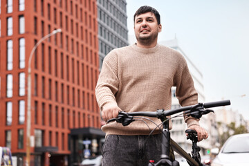 Man with bicycle outdoors, low angle view. Space for text