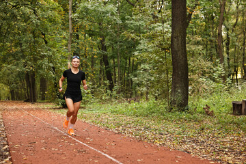 Athletic woman running in park, space for text