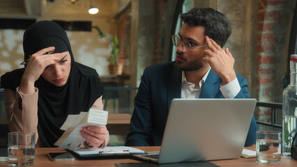Business colleagues Arabian man muslim woman in hijab bank payment laptop count bills check invoice financial problem account debt bankruptcy upset frustrated stressed businesswoman businessman office