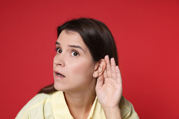 Woman showing hand to ear gesture on red background