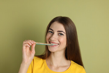 Young woman eating tasty rainbow sour belt on olive background