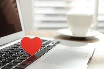 Red heart on laptop in office, space for text. Valentine's day celebration