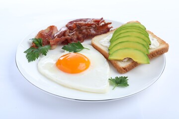 Romantic breakfast with fried bacon, heart shaped egg and avocado toast isolated on white. Valentine's day celebration