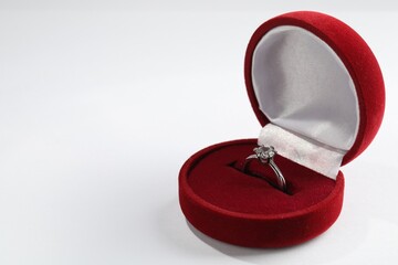 Beautiful engagement ring in red box on white background, space for text