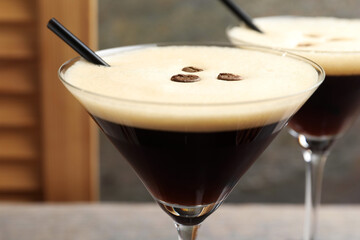 Glasses of delicious espresso martini with coffee beans on table, closeup