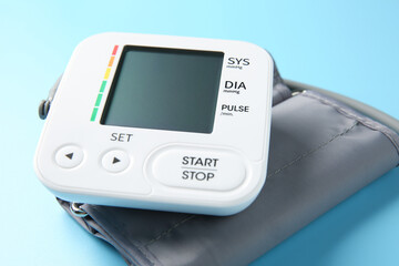 Blood pressure measuring device on light blue background, closeup