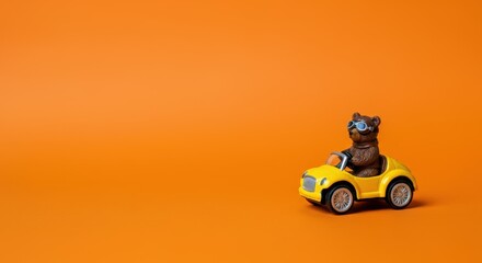 Obraz premium Toy bear in yellow car on orange background with childlike playfulness