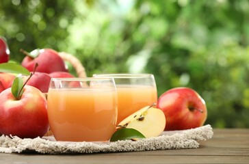 Tasty apple juice and fresh fruits on wooden table against blurred background