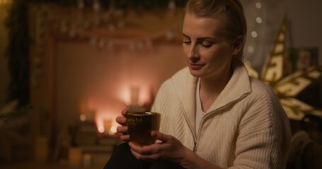 Woman Reminiscing About Old Times and Drinking Tea During the Holidays in a Cozy Living Room Late in the Evening