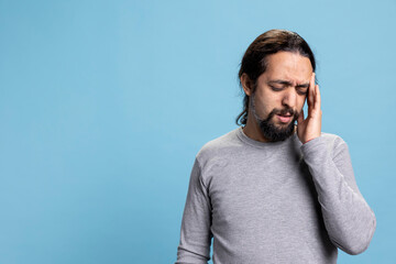 Young adult feeling overwhelmed and worried about his migraine, getting sick and overworked due to...