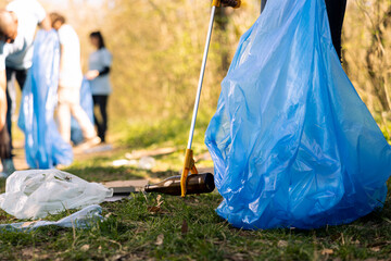 Volunteers group gathering to tidy up the woods of garbage, fighting forest pollution to protect...