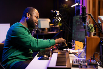 Talented musician creating new soundtracks on mixing console, operating on audio equipment in home...