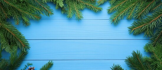 Spruce branches and festive decorations on a blue wooden background creating a cozy holiday atmosphere with space for personalization