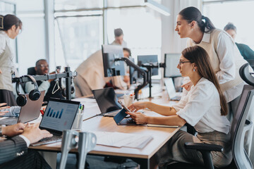 Multicultural team working together in a modern office setting. Focus on teamwork, collaboration, and diverse perspectives, with employees engaging over laptops and digital devices.