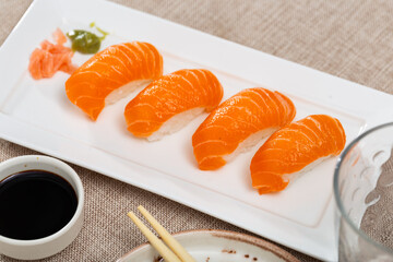 Nigiri with salmon dished up in service plate with soya-bean sauce and necessary table laying