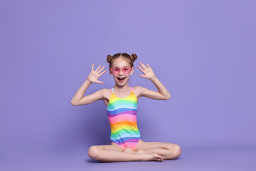 Happy girl in beachwear on purple background