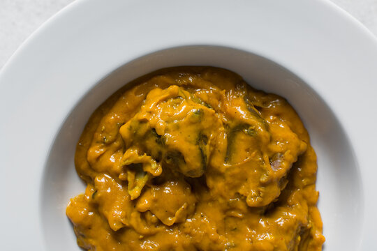 Overhead view of Nigerian owo soup with fish and beef in a white plate, top view of oghwo soup in a large dinner plate, traditional owo soup in a white dish