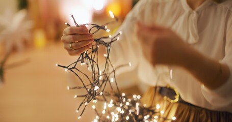 Woman Untangling Christmas Lights in Warm Interior